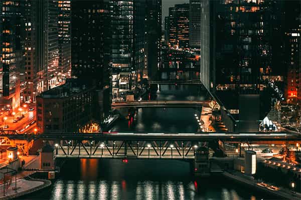 waterway through a central business district with bridges and building illuminated at night